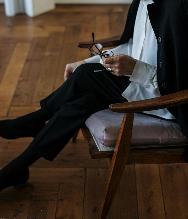 Woman in elegant office clothes doing a calming stretch at her modern workspace.